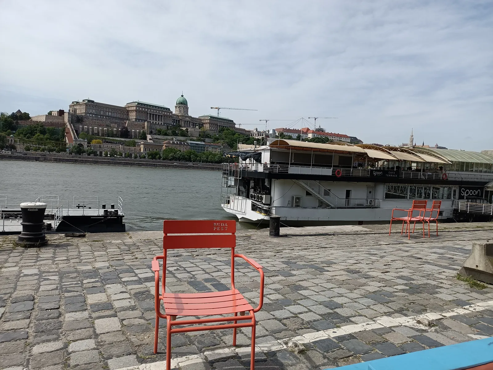 Krzesło z napisem „Budapest” na nabrzeżu Pesztu, w tle Zamek Królewski na Wzgórzu Zamkowym