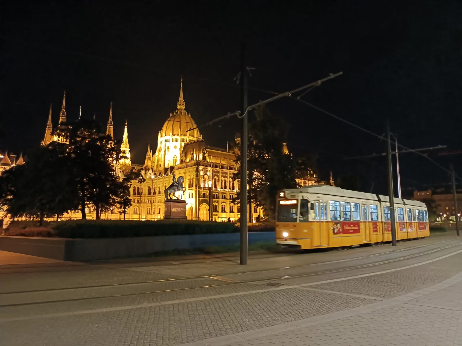 Parlament nocą i żółty tramwaj linii 2 przy placu Kossutha